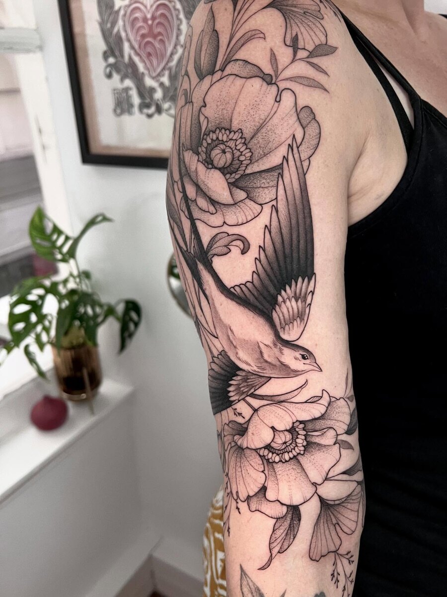 Manchette florale en blackwork, pivoines et oiseau sur le bras