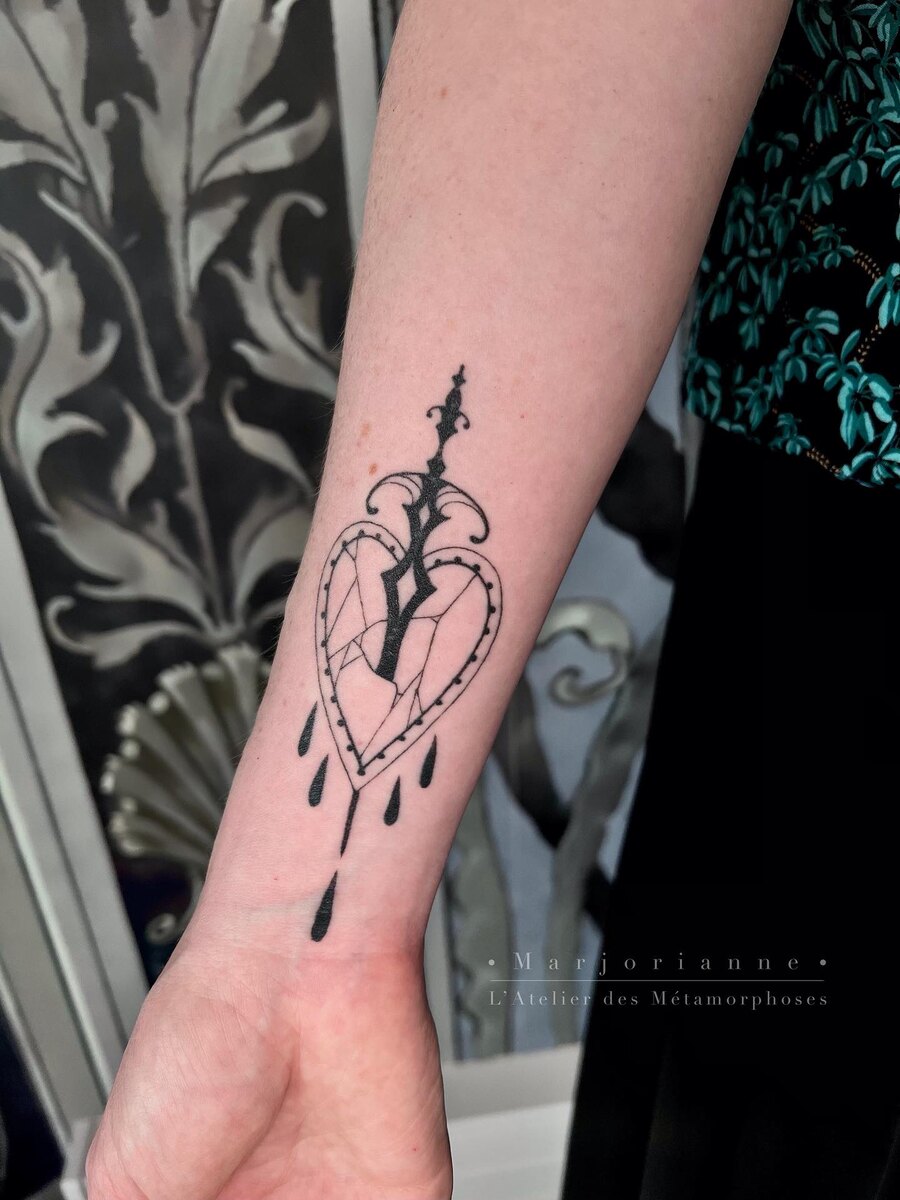 Cœur ornemental tatoué sur l'avant-bras, lignes fines à l'encre noire